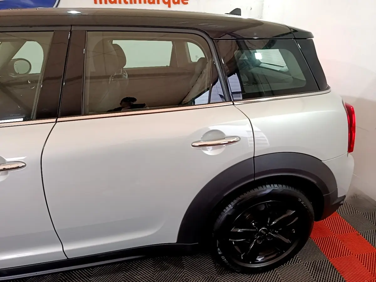 Vue latérale droite d'un MINI Countryman gris clair avec toit noir et jantes noires brillantes.