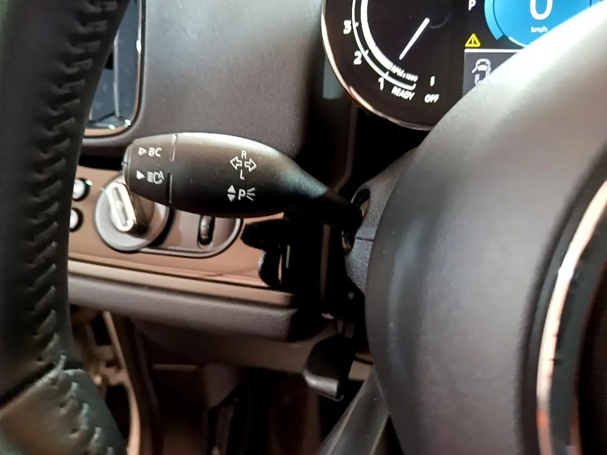 Gros plan sur la commande de clignotants à gauche du volant cuir du MINI Countryman gris clair, tableau de bord partiellement visible.