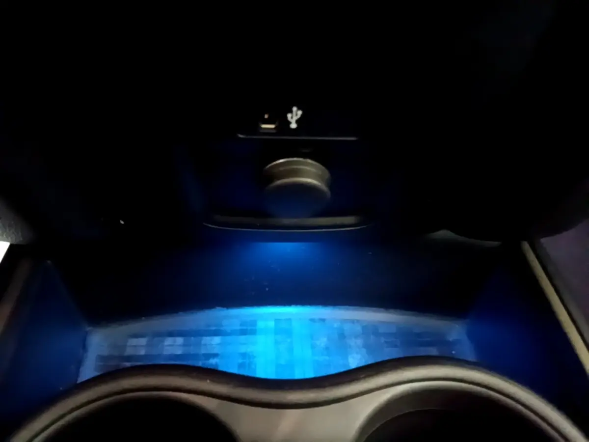 Gros plan sur la zone de recharge par induction avec éclairage d'ambiance bleu dans le coffre avant du MINI Countryman gris clair.