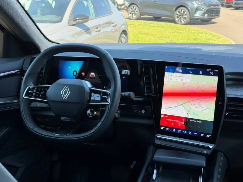 Vue intérieure du tableau de bord du Renault Austral gris Schiste 2024, avec volant multifonction et grand écran tactile vertical.
