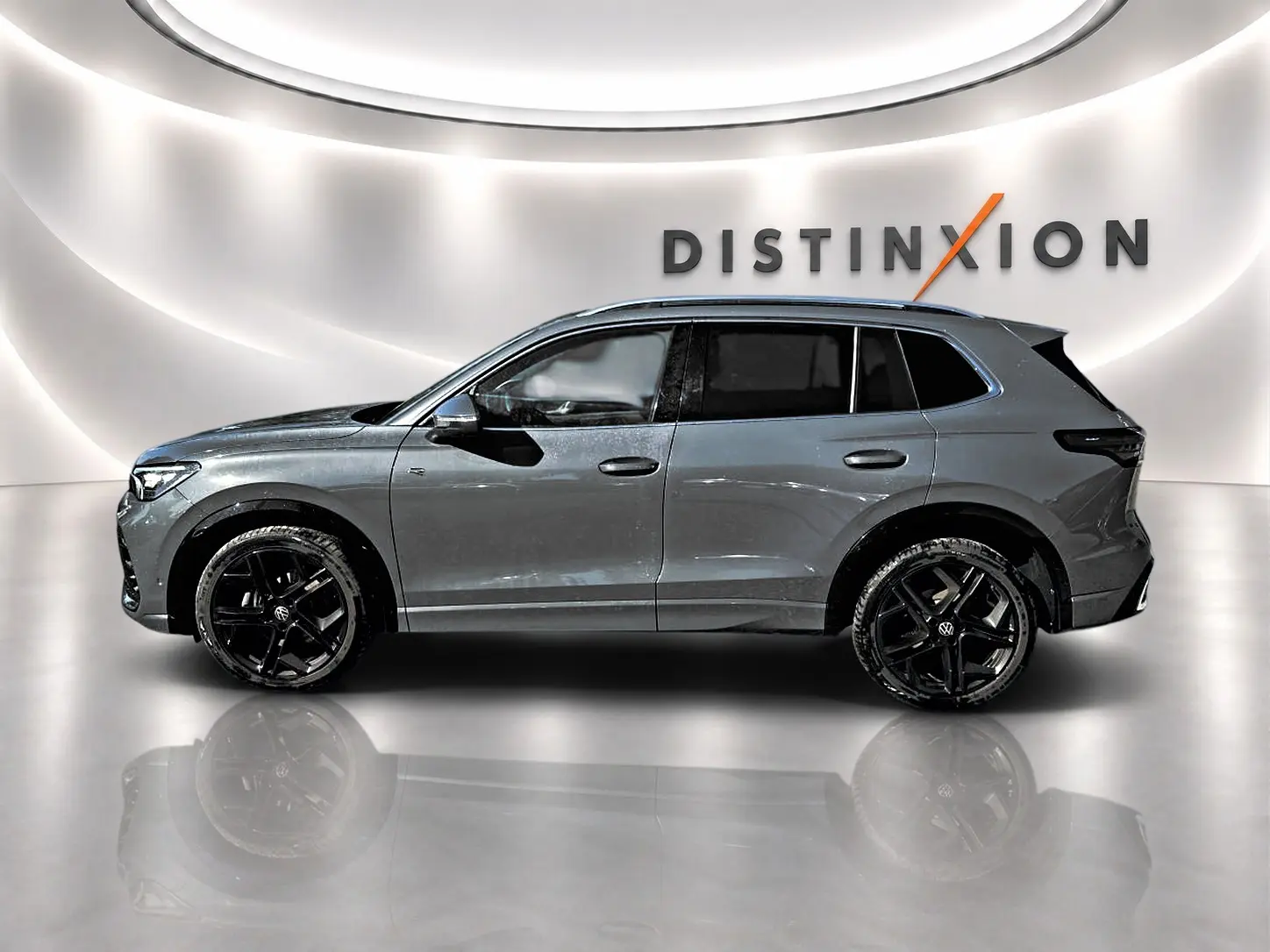 Volkswagen Tiguan 2024 gris dauphin en profil gauche, jantes noires et toit panoramique visible.