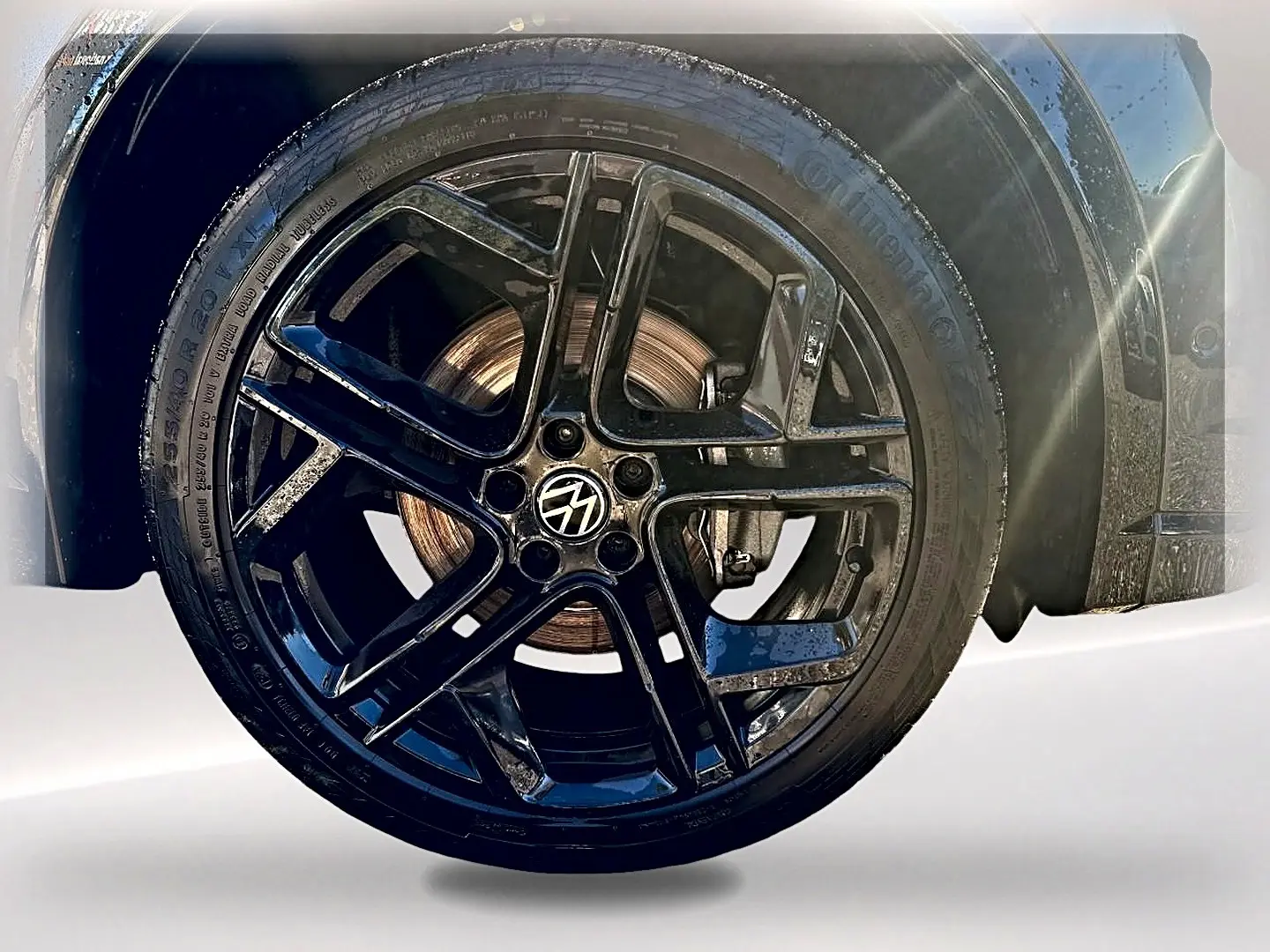 Gros plan sur la jante alu noire brillante du Volkswagen Tiguan gris dauphin, mettant en valeur le logo VW central.
