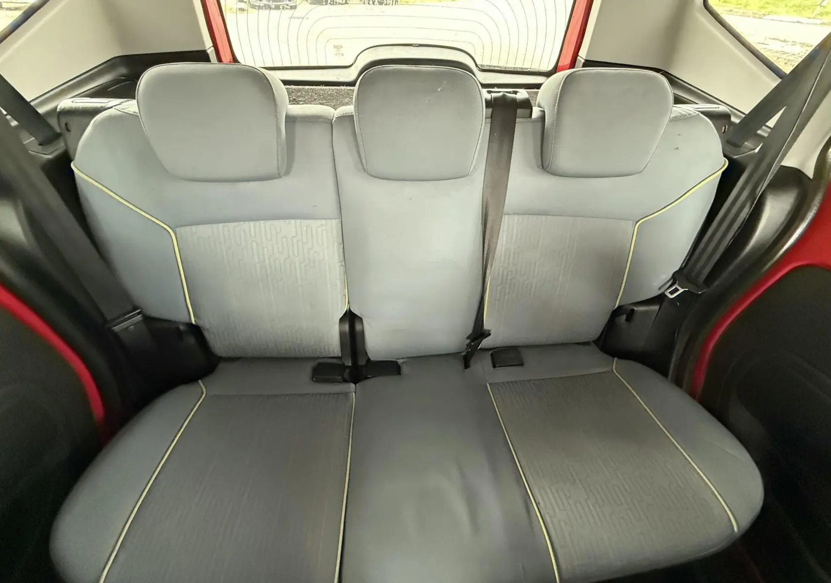 Vue intérieure arrière de la banquette grise avec surpiqûres jaunes du Peugeot Bipper Tepee rouge visible sur les côtés.