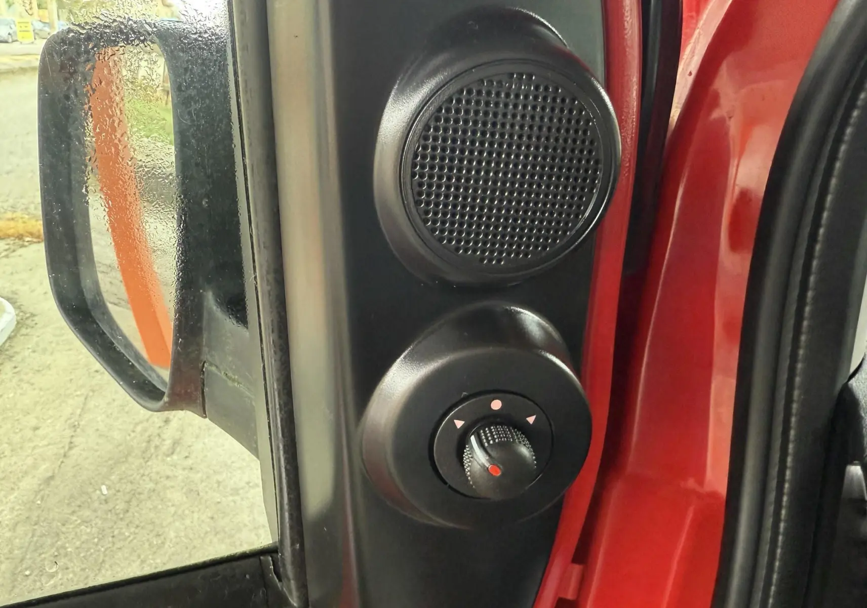 Gros plan sur le réglage du rétroviseur et haut-parleur côté gauche d'une Peugeot Bipper Tepee rouge.