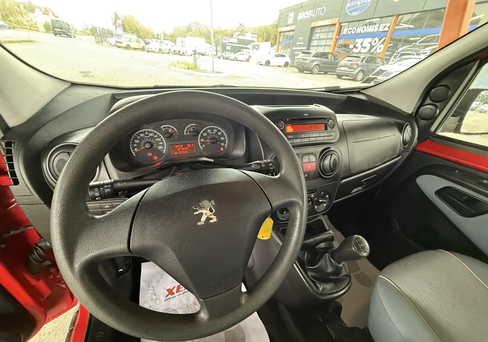 Vue intérieure du poste de conduite du Peugeot Bipper Tepee rouge de 2013, volant et tableau de bord visibles.