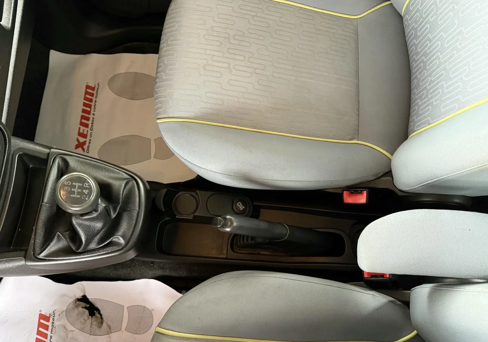 Vue plongeante sur la console centrale d'un Peugeot Bipper Tepee 2013 avec levier de vitesses manuel et sièges gris à liseré jaune.