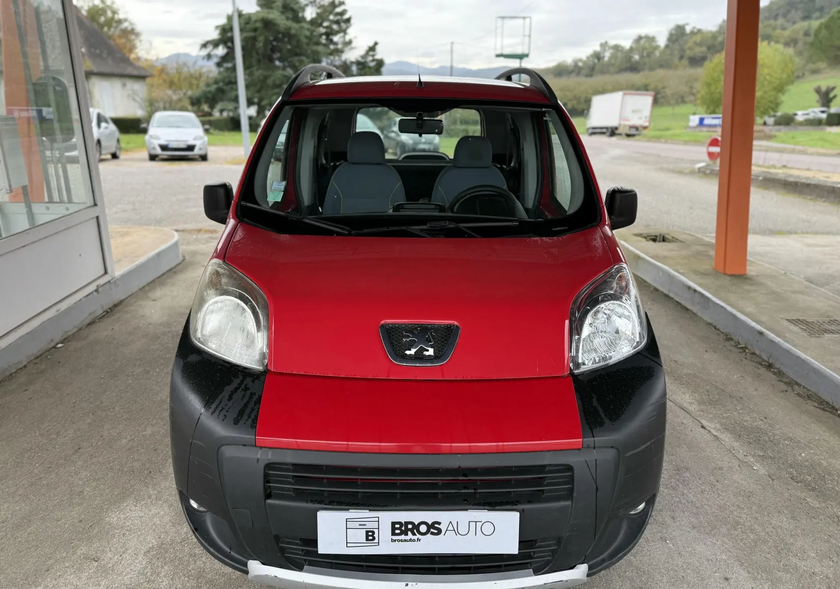 Vue frontale d'un Peugeot Bipper Tepee rouge avec pare-chocs noir et toit équipé de barres de toit.