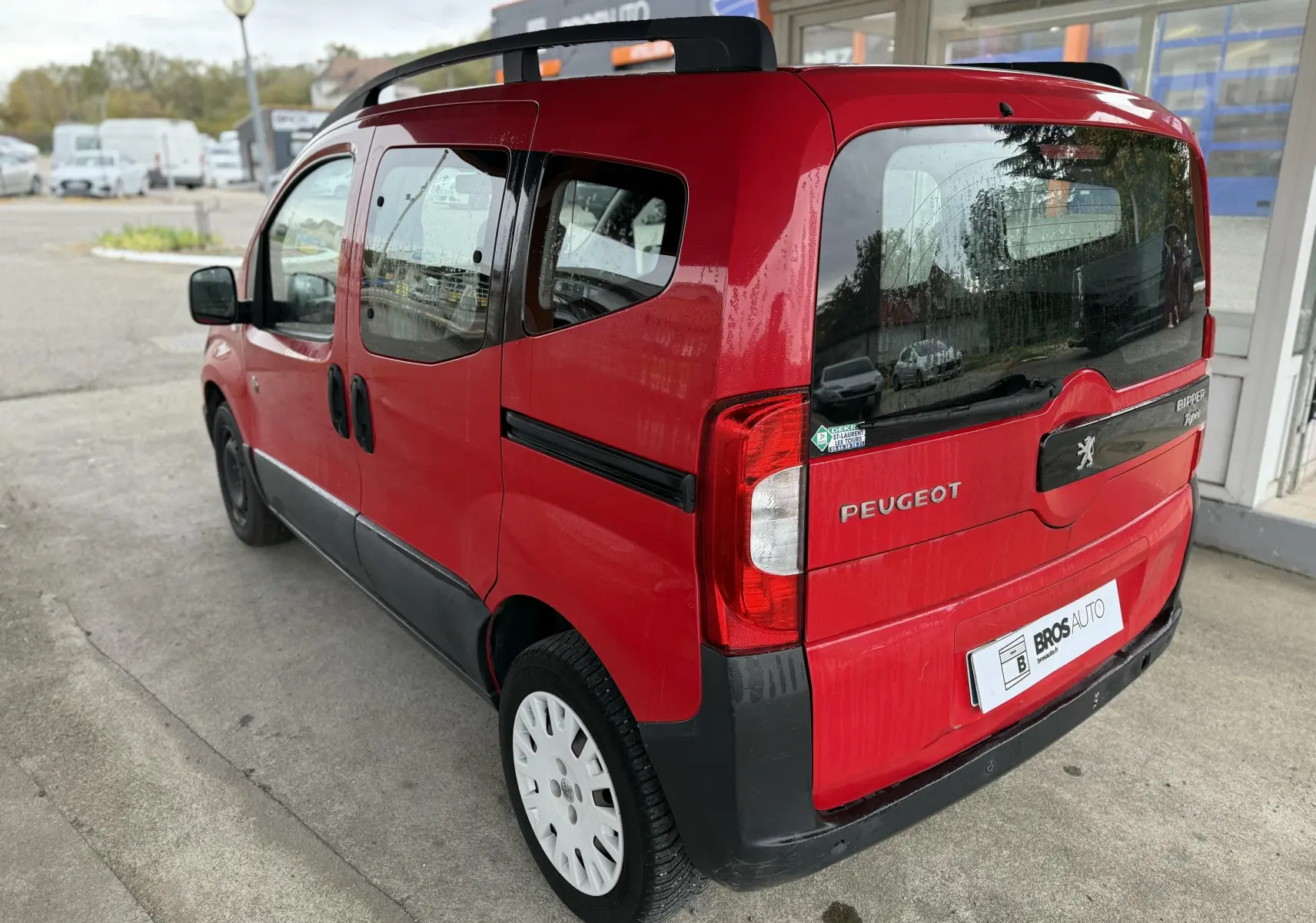 Vue 3/4 arrière droite d'un Peugeot Bipper Tepee rouge avec portes coulissantes et jantes blanches.