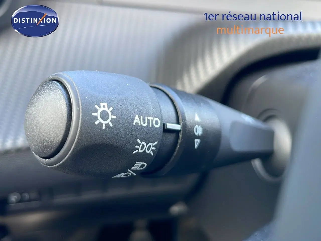 Gros plan sur la commande des phares automatiques dans l’habitacle d’une Peugeot 2008 blanche Okenite Metal 2025.