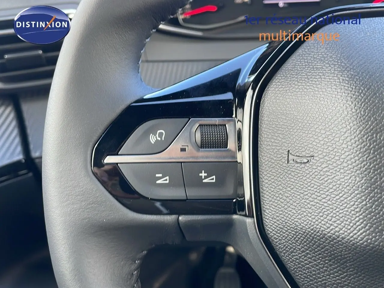 Gros plan sur les commandes gauche du volant noir du Peugeot 2008 blanc Okenite Metal 2025.