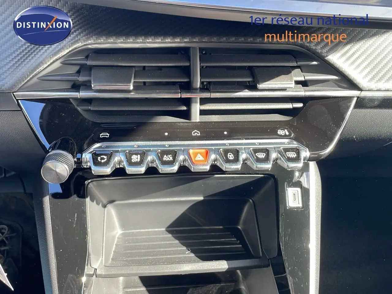 Vue rapprochée de la console centrale noire brillante du Peugeot 2008 blanc Okenite, avec commandes tactiles et aérateurs.