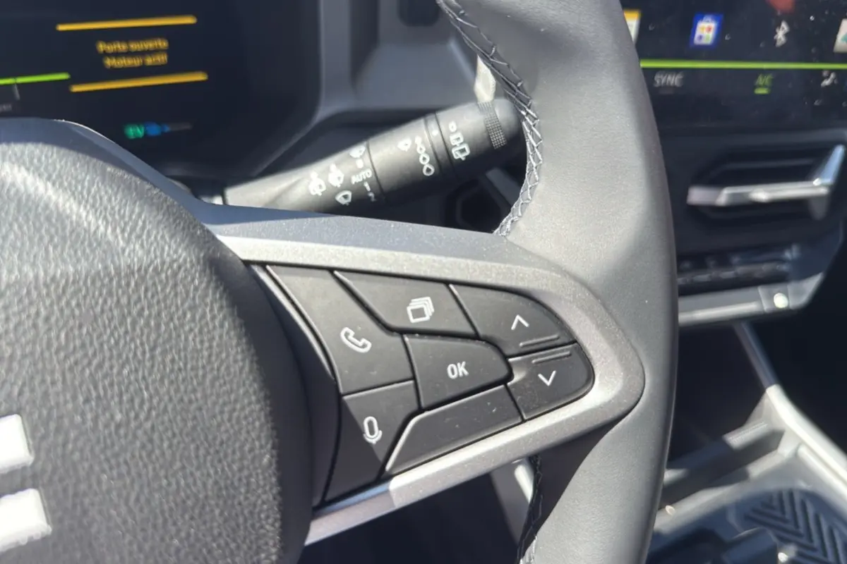 Gros plan sur les commandes au volant cuir du Dacia Bigster Hybrid 155 gris schiste, avec tableau de bord digital en arrière-plan.