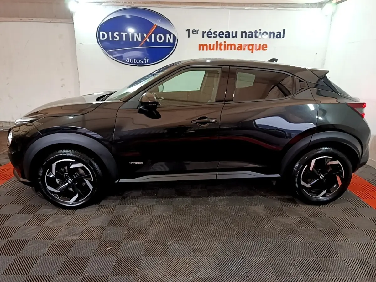 Profil droit d'un Nissan Juke Hybrid 143 Business+ noir, avec jantes noires et logo Hybrid visible sur la porte.