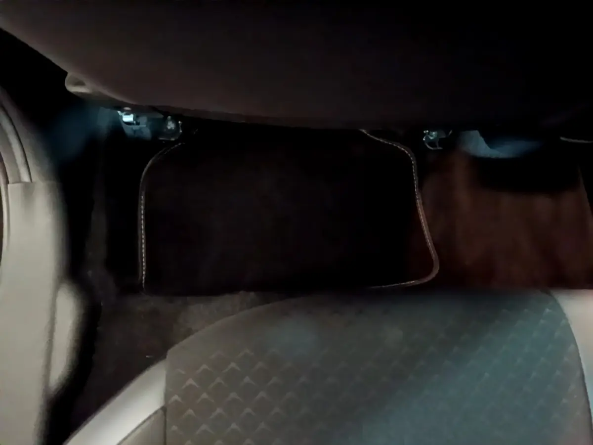 Vue du sol côté passager arrière du Nissan Juke Hybrid 143 Business+ 2022, tapis de sol noir et siège gris foncé.