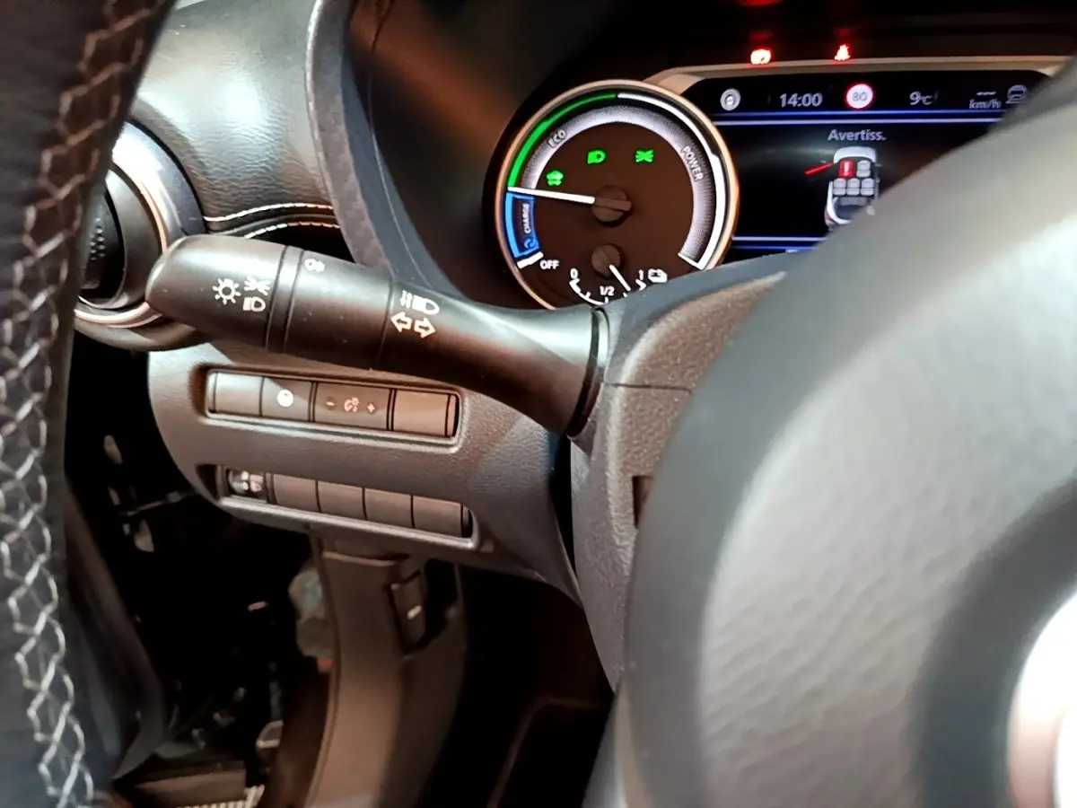 Gros plan sur le tableau de bord et le combiné d'instruments du Nissan Juke Hybrid noir, avec affichage digital et commandes au volant.