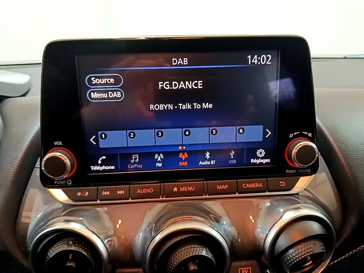 Écran tactile central 8 pouces du Nissan Juke Hybrid 2022 montrant l'interface radio DAB avec commandes audio et climatisation.