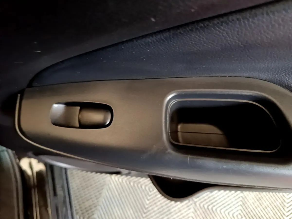 Détail de la poignée intérieure noire côté conducteur du Nissan Juke Hybrid 2022, finition Business+