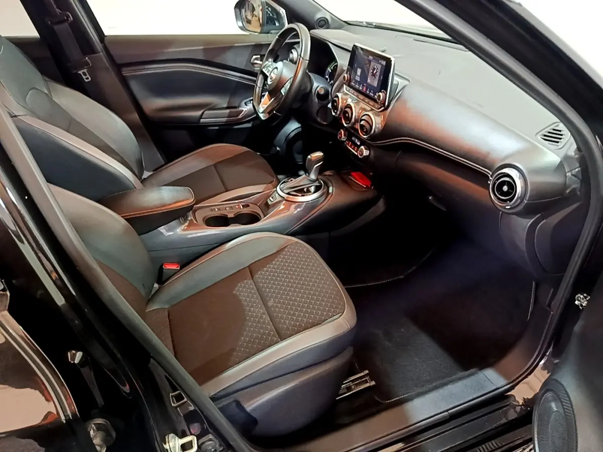 Intérieur côté conducteur du Nissan Juke Hybrid 2022 noir, avec tableau de bord moderne et écran tactile central.