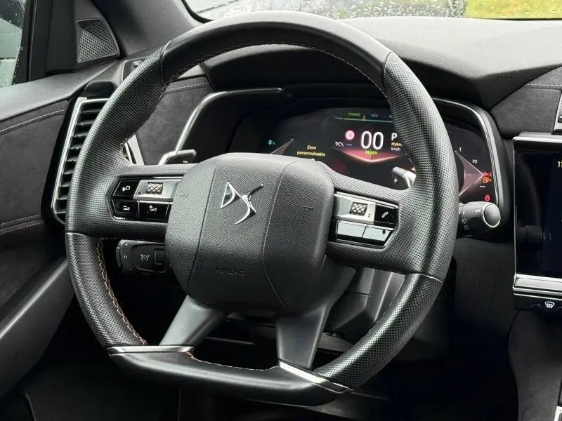 Vue rapprochée du volant noir perforé du DS7 E-TENSE 225ch 2024 avec tableau de bord numérique et finitions en alcantara gris.