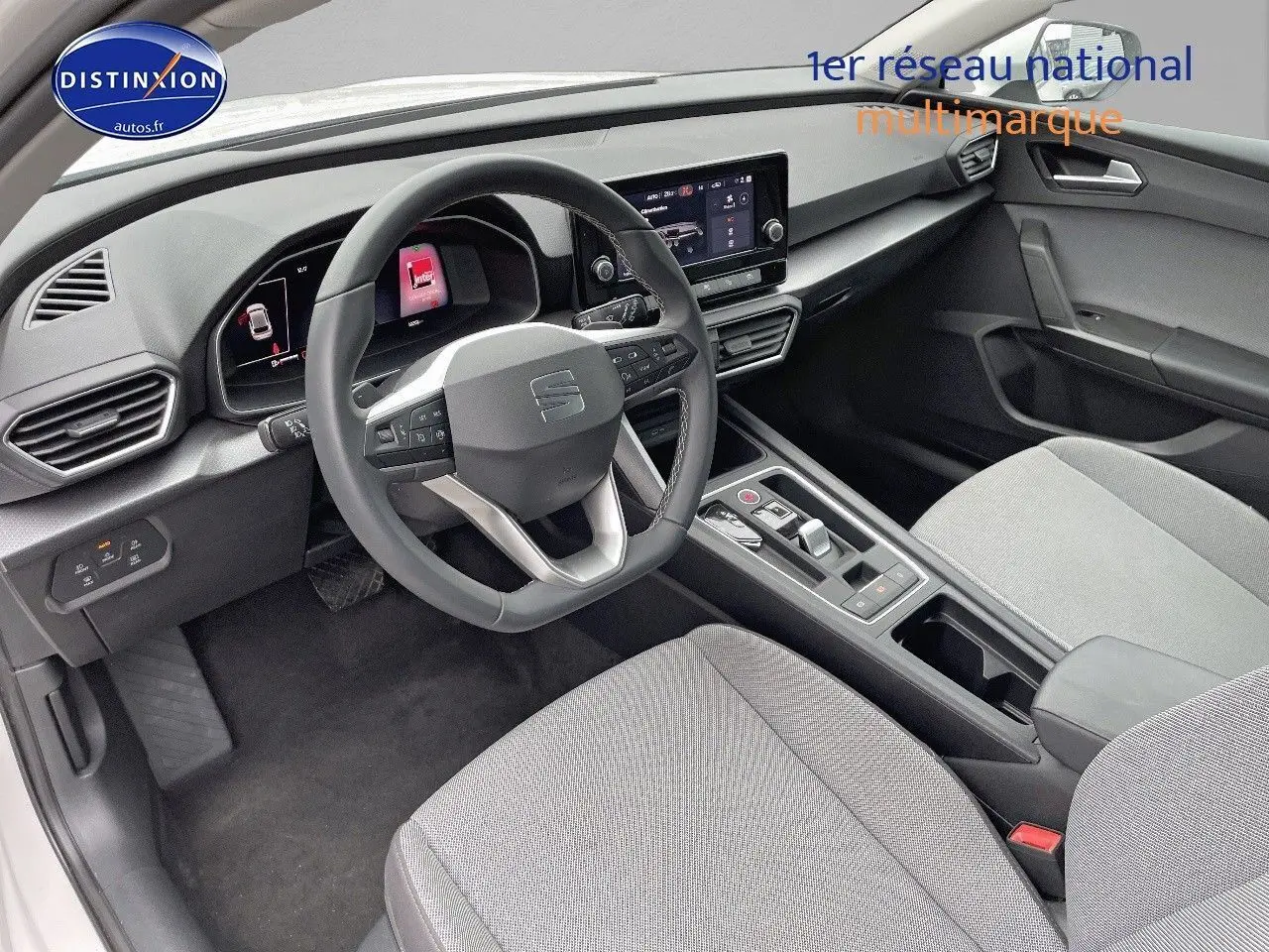 Intérieur de la SEAT LEON IV 2024 en tissu gris, vue côté conducteur montrant le tableau de bord et volant multifonction.