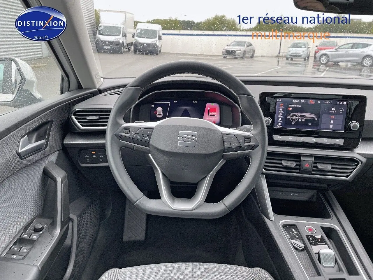 Vue intérieure centrée sur le volant et tableau de bord numérique d'une SEAT Leon IV blanche de 2024.