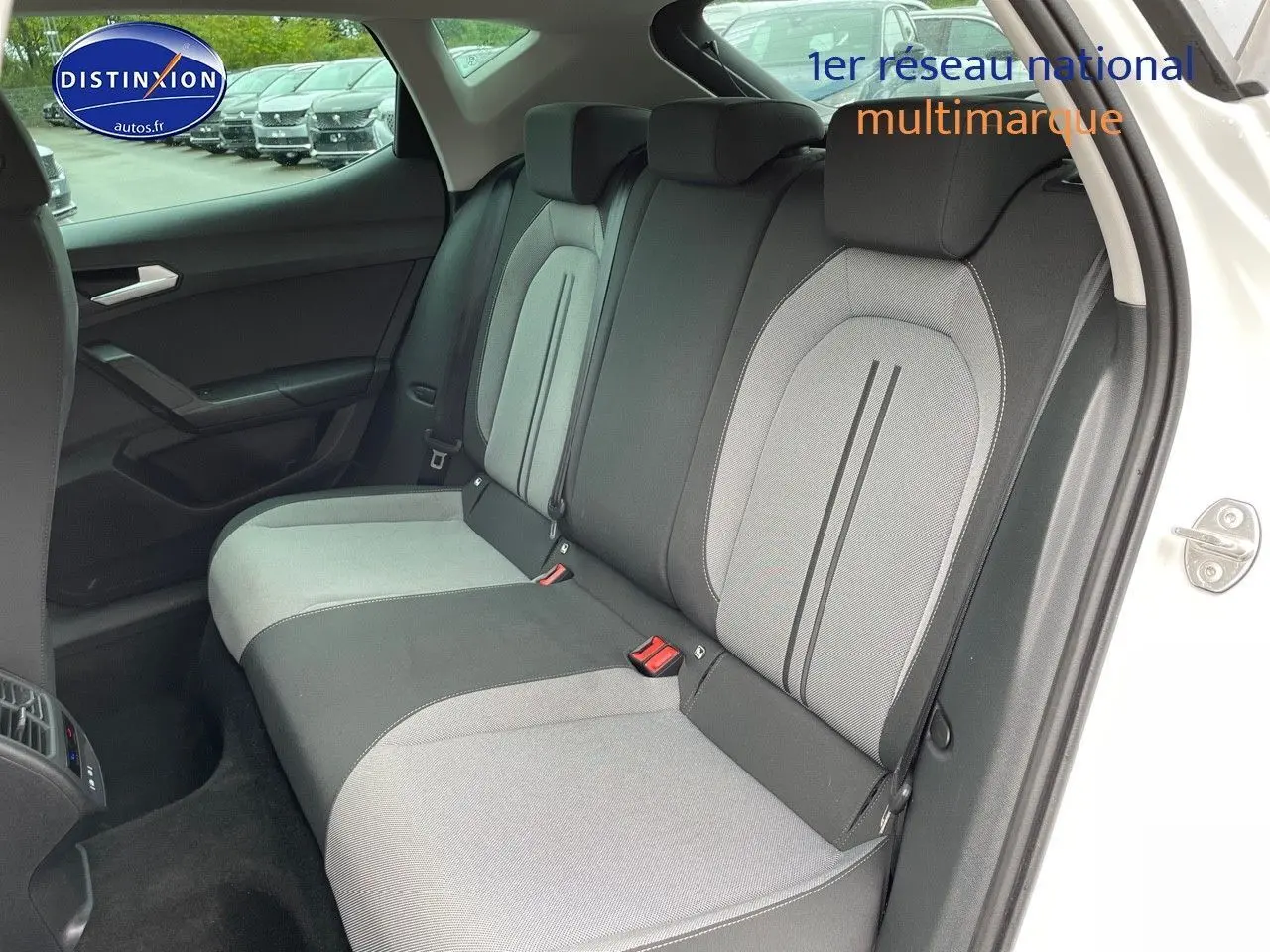 Vue intérieure arrière côté gauche du SEAT LEON blanc 2024, montrant les sièges arrière bicolores gris et noir.