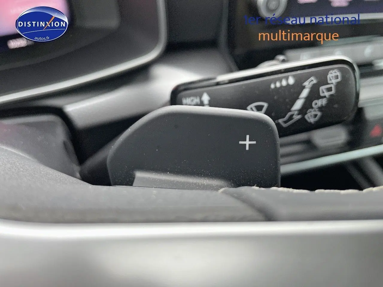 Gros plan sur la palette de changement de vitesse "+" du volant d'une SEAT LEON blanche 2024, intérieur moderne.