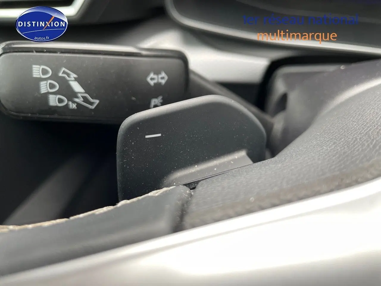 Gros plan sur la palette de changement de vitesses au volant d'une SEAT LEON blanche 2024, intérieur noir.