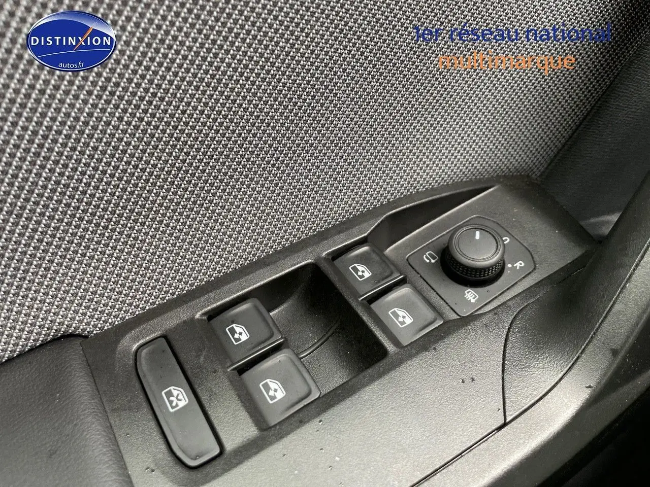 Panneau de commandes des vitres et rétroviseurs côté conducteur d'une SEAT Leon blanche 2024, intérieur tissu gris.