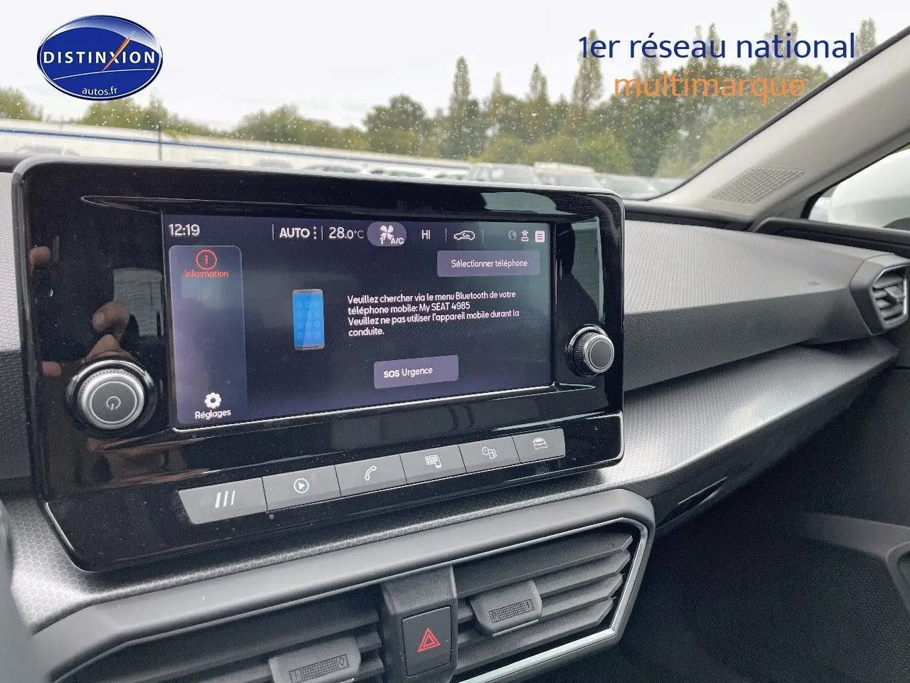 Tableau de bord et écran tactile central du SEAT LEON IV blanc, vue intérieure côté passager avec détails modernes et climatisation.