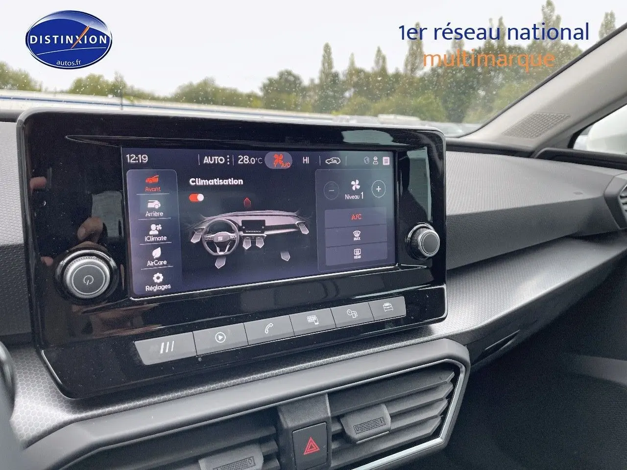 Vue rapprochée de l'écran tactile central du tableau de bord d'une SEAT Leon blanche 2024, affichant la climatisation.