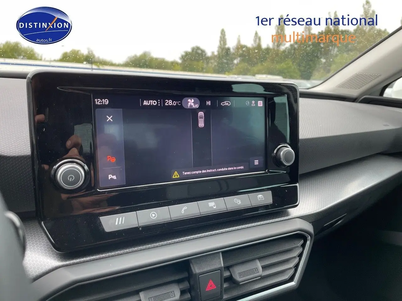 Vue intérieure du tableau de bord de la SEAT LEON IV blanche, avec écran tactile central et commandes climatisation visibles.