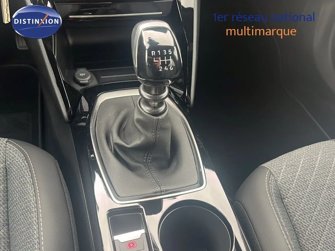 Le levier de vitesses manuel noir au centre de la console d'une Peugeot 2008 blanche, avec sièges gris en tissu.