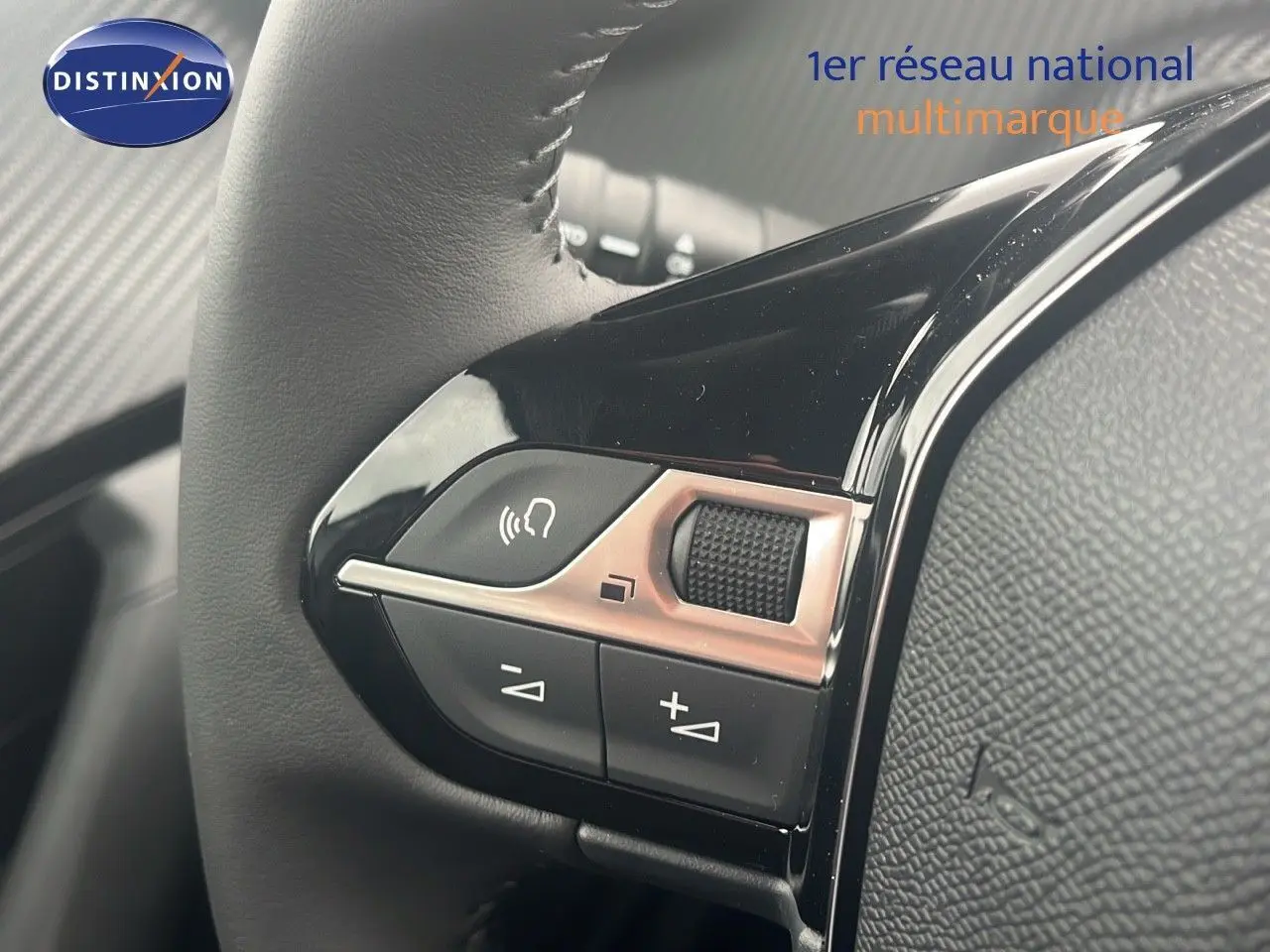 Gros plan sur les commandes au volant noir brillant du Peugeot 2008 blanc Okenite Metal, version 2025.