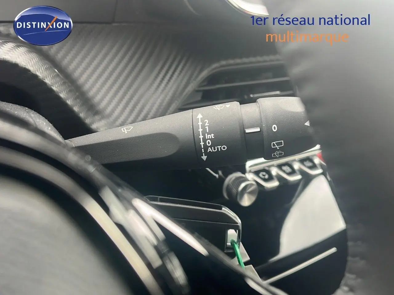 Gros plan sur la manette d'essuie-glace à gauche du volant dans l'habitacle du Peugeot 2008 blanc Okenite Metal.