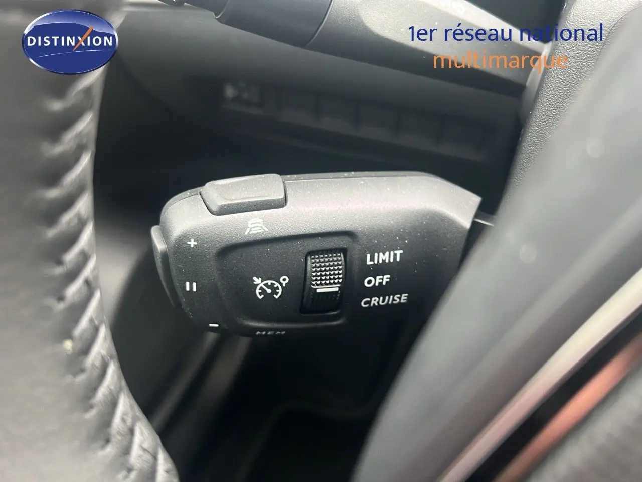 Gros plan sur la commande de régulateur de vitesse du Peugeot 2008 blanc Okenite, côté gauche du volant.