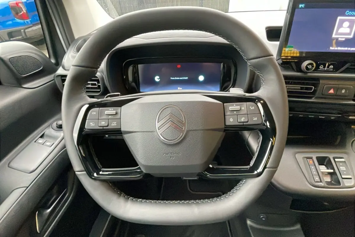 Vue centrée du volant noir du Citroën Berlingo 2025 avec commandes intégrées et tableau de bord numérique.