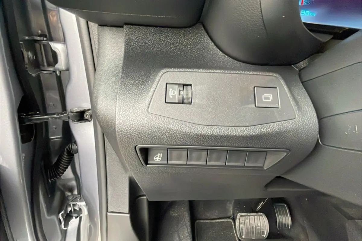 Gros plan sur les commandes côté gauche du tableau de bord du Citroën Berlingo 2025 gris artense, avec pédales visibles.