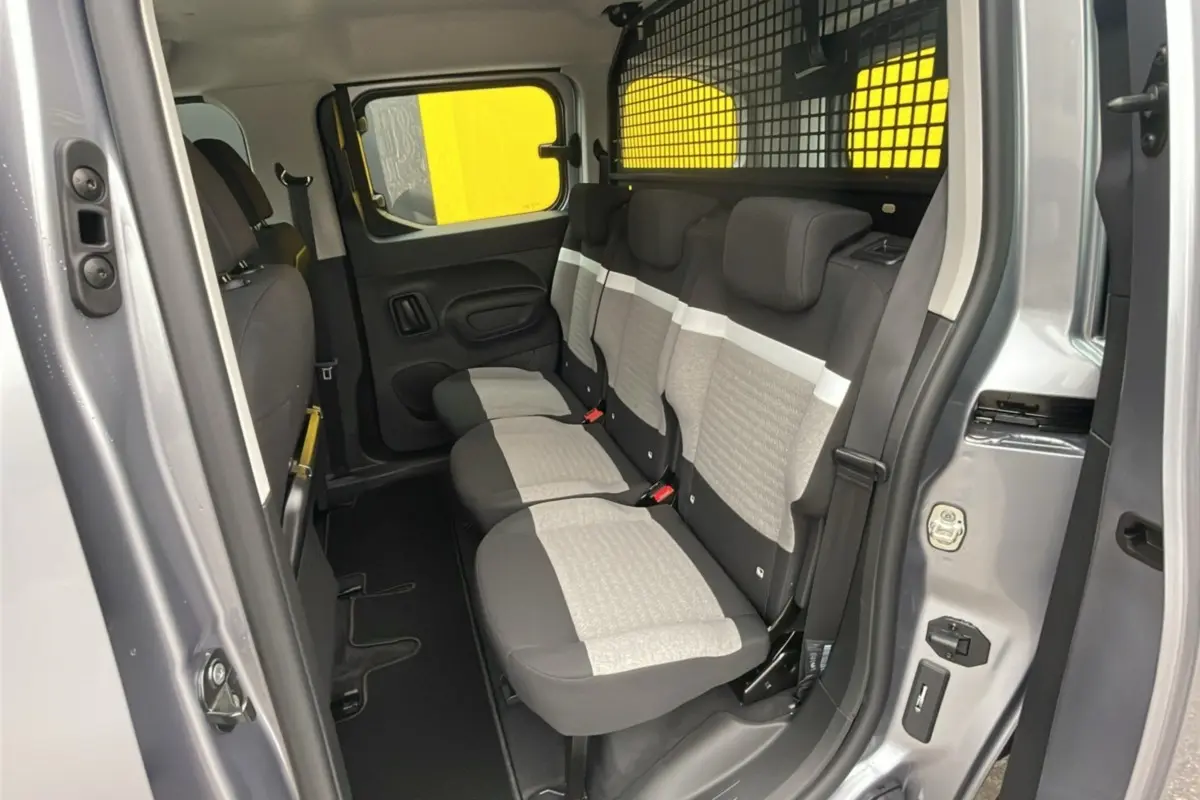 Vue intérieure côté droit du Citroën Berlingo 2025 gris artense, montrant la banquette arrière trois places avec grille de séparation.