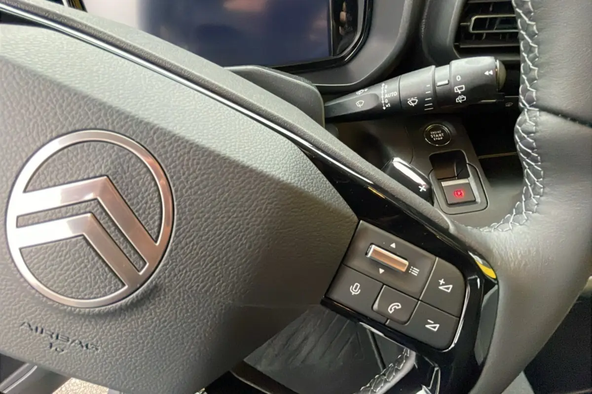 Gros plan sur le volant en cuir du Citroën Berlingo 2025 gris artense avec commandes audio et bouton start/stop visibles.
