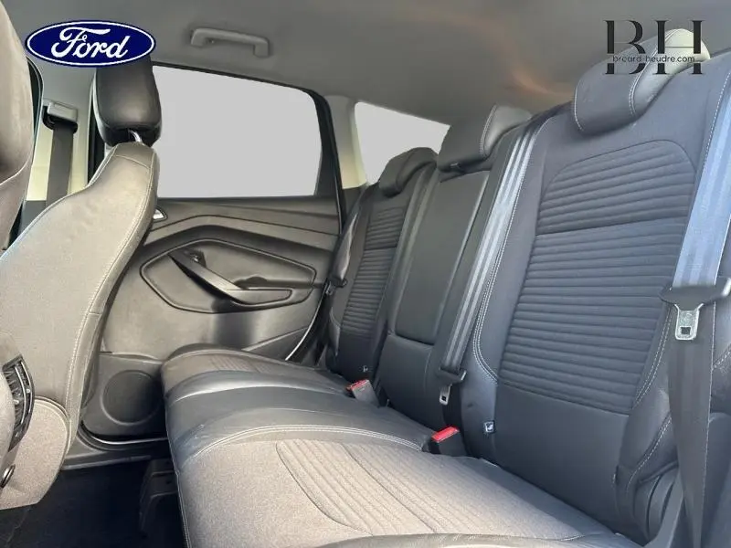 Vue intérieure sur la banquette arrière en tissu noir du Ford Kuga 2017, soulignant les ceintures et appuie-têtes.