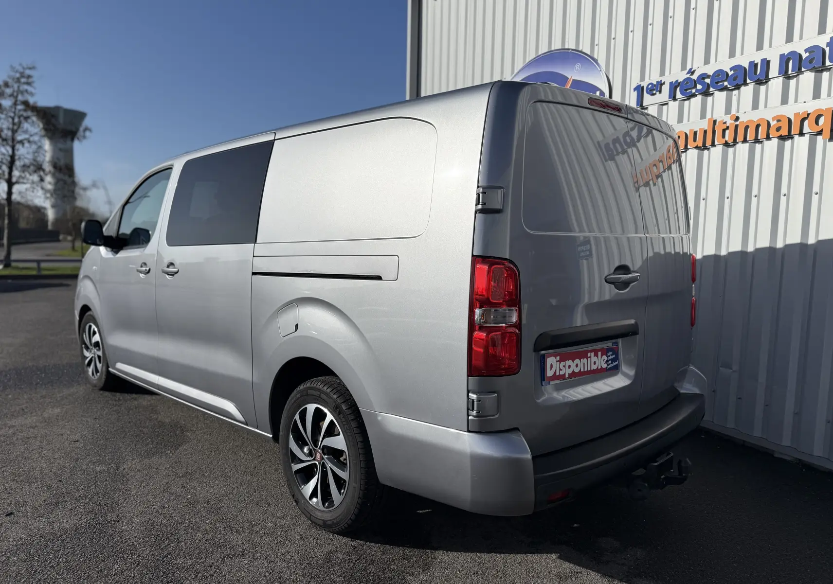 Vue 3/4 arrière droite d’un FIAT Scudo cabine approfondie gris 2022 avec jantes bi-ton et attelage visible.