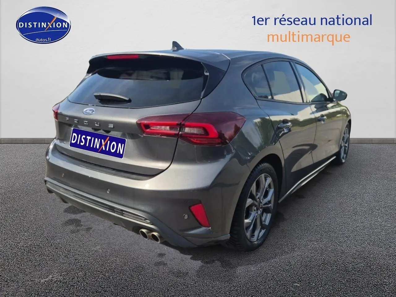 Ford Focus 2024 gris magnétique vue 3/4 arrière droit avec double sortie d'échappement et becquet arrière.