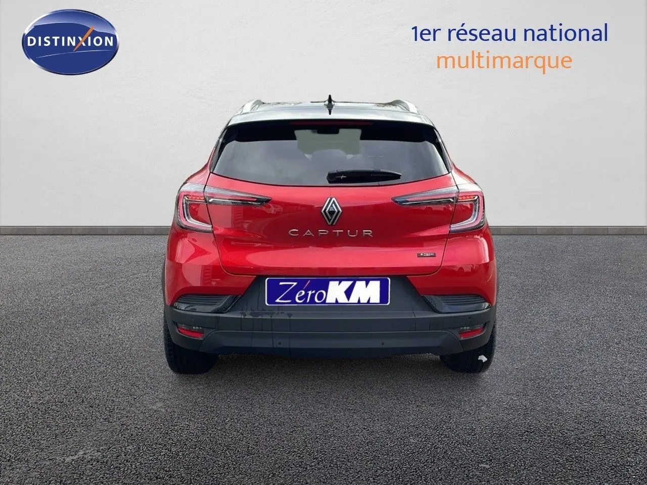 Vue arrière d'un Renault Captur E-Tech hybride rouge passion avec toit noir et plaque Zéro KM visible.