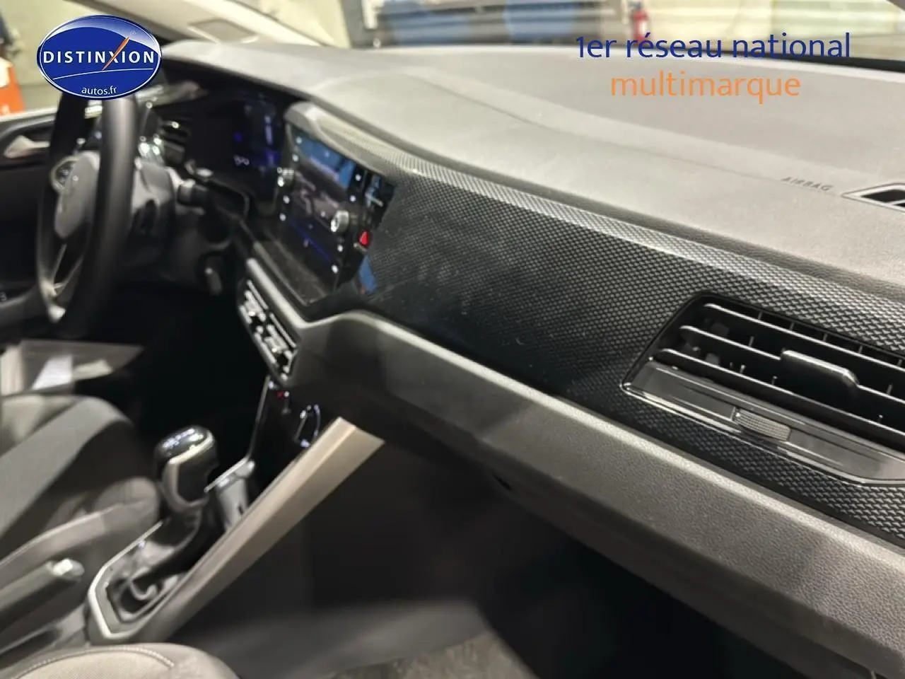 Vue intérieure côté passager montrant le tableau de bord noir avec décor lava stone black et la console centrale d'une Volkswagen Polo gris cendre.