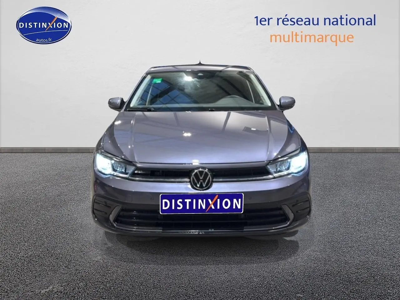 Vue avant d'une Volkswagen Polo gris cendre 2025 avec phares LED allumés et calandre noire distinctive.