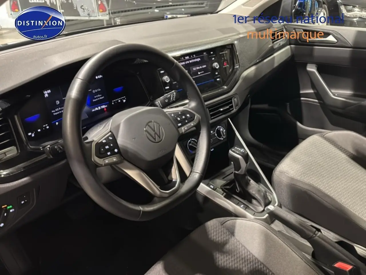 Vue intérieure côté conducteur de la Volkswagen Polo gris cendre 2025 avec volant cuir multifonction et écran tactile central.