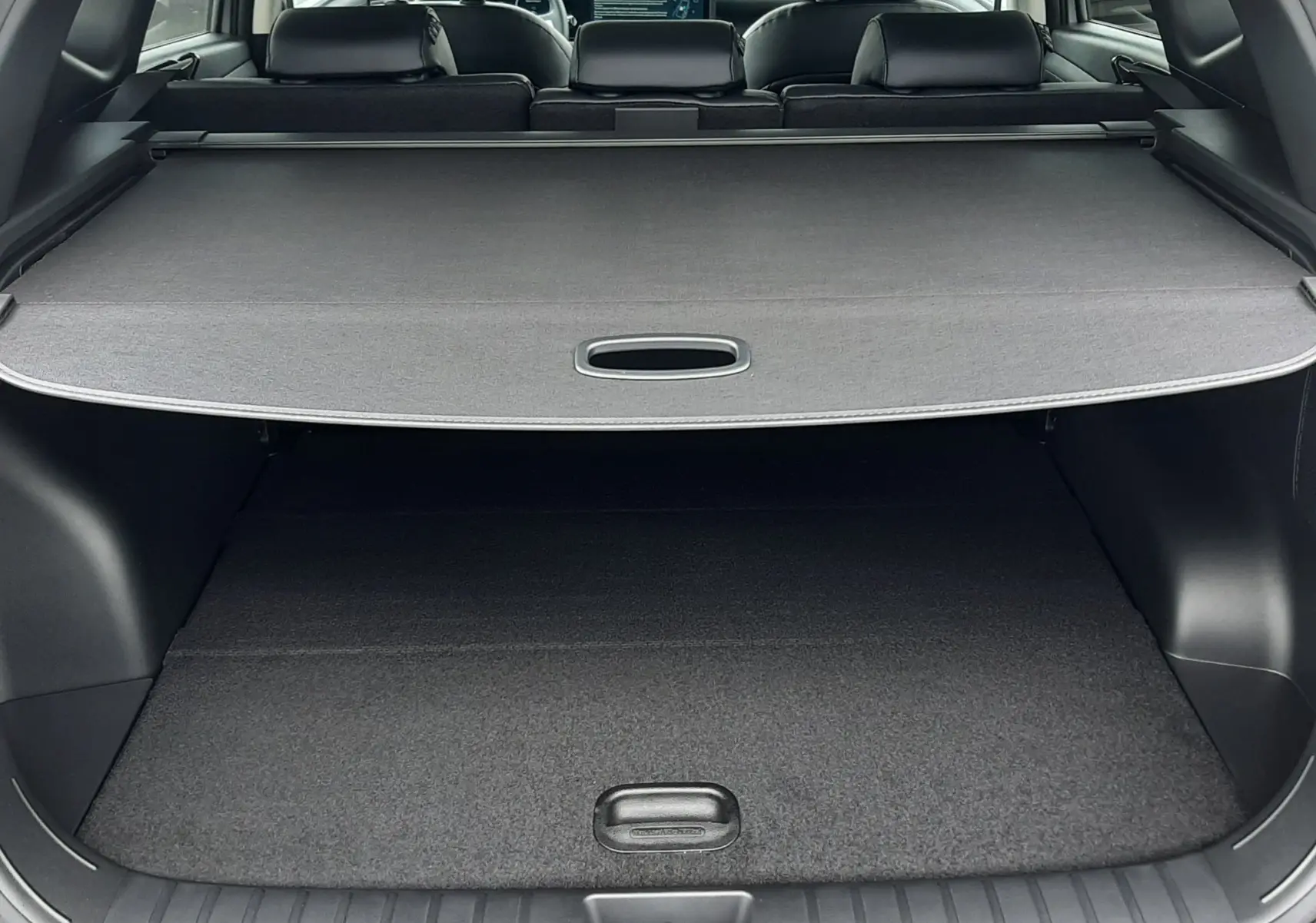 Vue arrière du coffre du Hyundai Tucson gris Shimmering Silver 2025, avec cache-bagages déployé et intérieur noir visible.