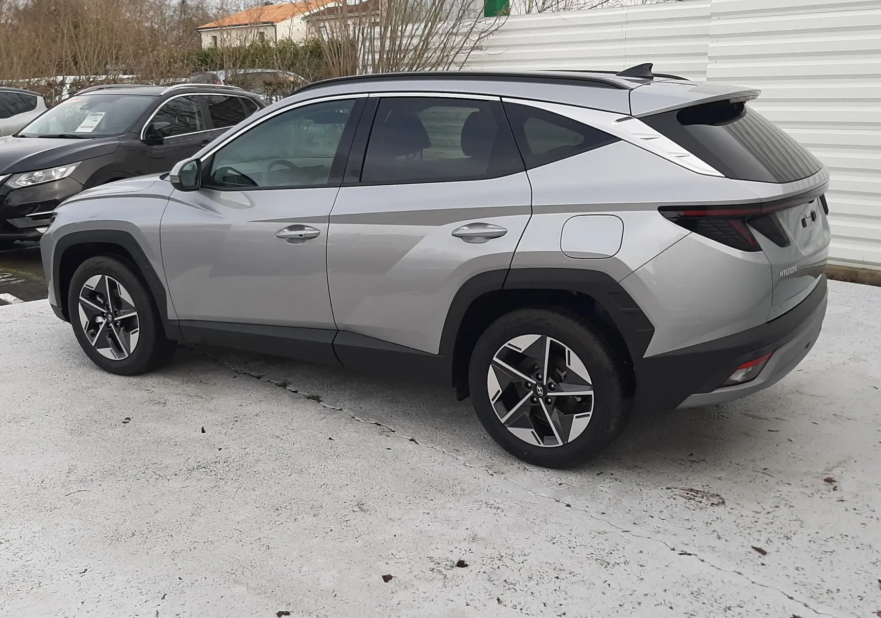 Vue côté droit arrière du Hyundai Tucson 2025 gris Shimmering Silver avec jantes bi-ton et feux arrière LED distinctifs.