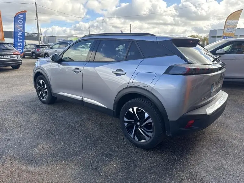 Peugeot 2008 gris Artense vue 3/4 arrière droit, avec jantes alliage bi-ton et barres de toit noires.
